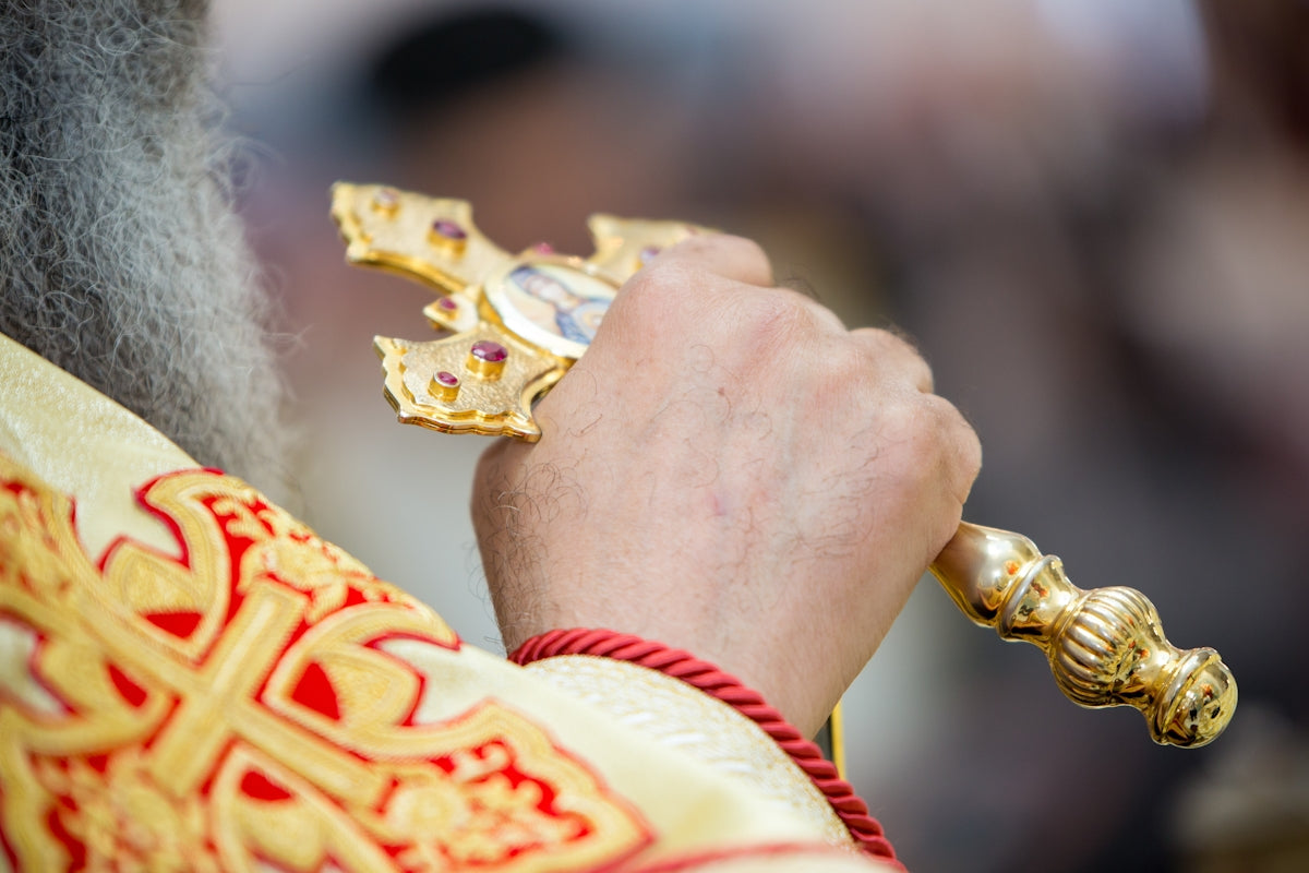 A close up of a priest holding a cross
