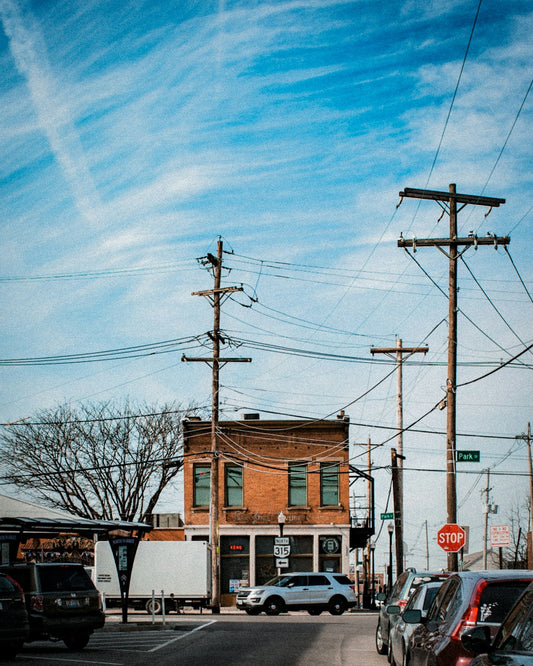cars on road while other cars parked at roadside near buildings at daytime
