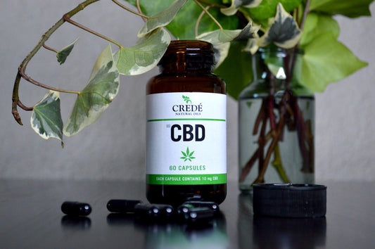 a bottle of cbd sitting next to a vase of flowers