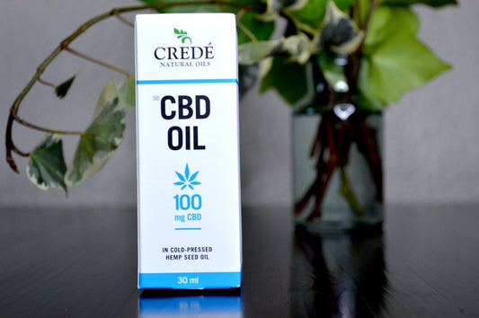 a bottle of cbd oil next to a vase of flowers