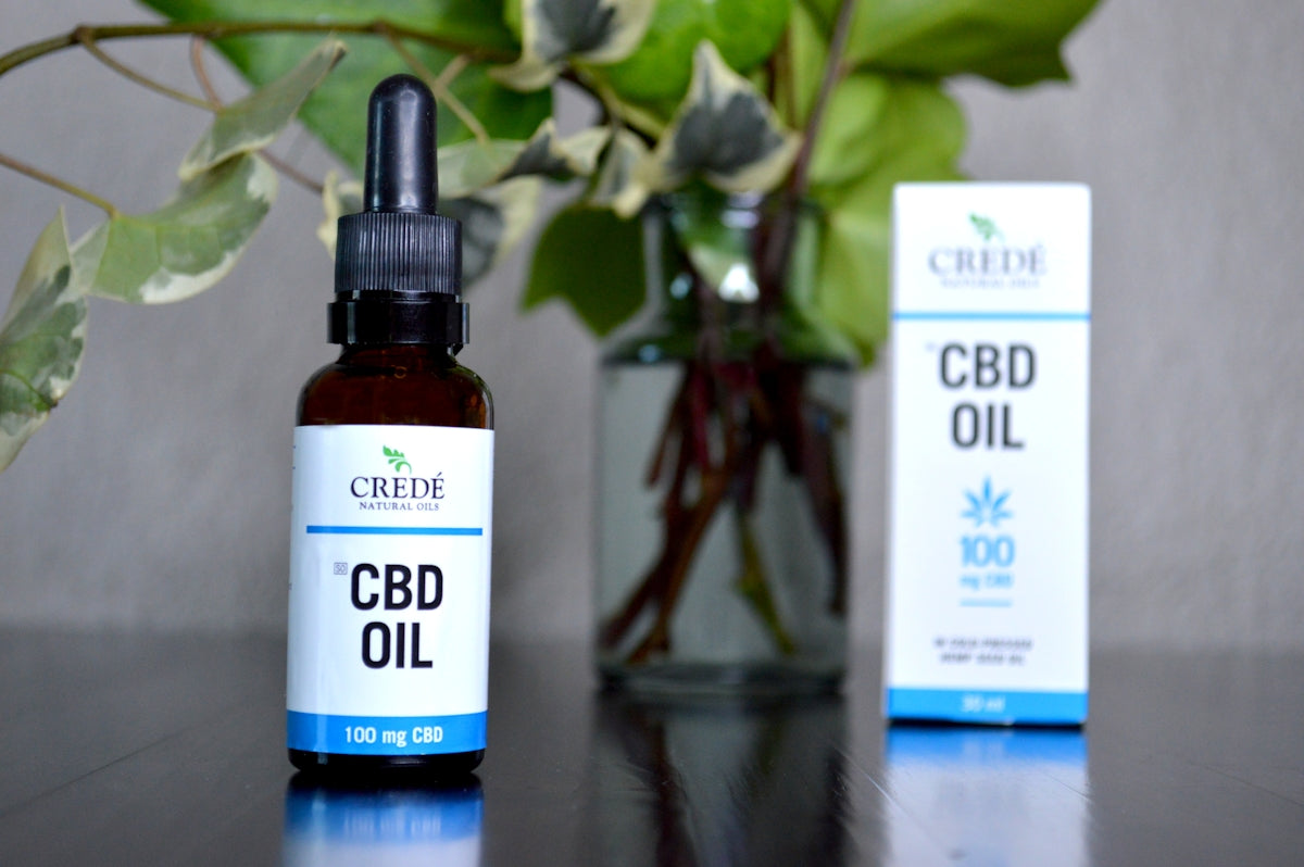 a bottle of cbd oil next to a vase of flowers