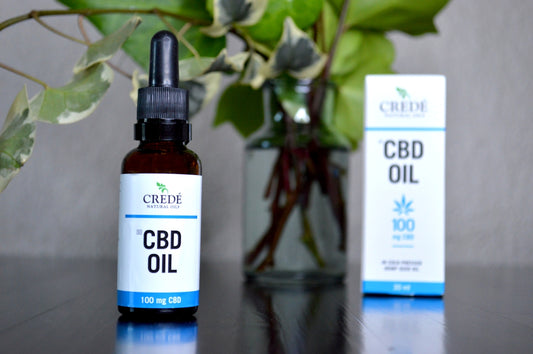 a bottle of cbd oil next to a vase of flowers