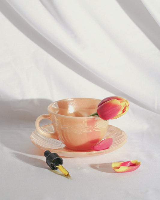 a cup with a flower in it sitting on a saucer