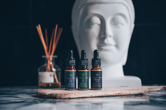 A buddha statue with three bottles of essential oils next to it