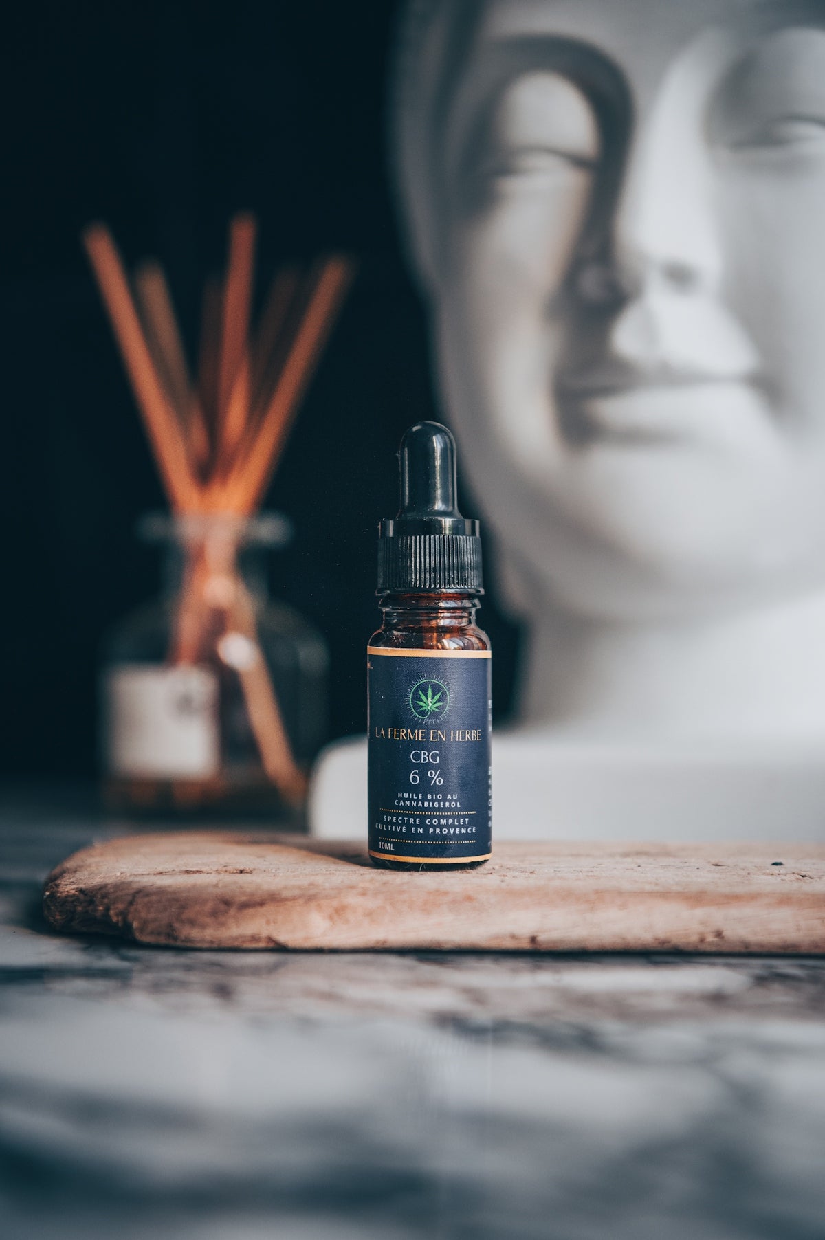 A buddha statue next to a bottle of essential oil