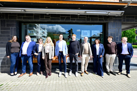 Ten business professionals standing together outside an office building.